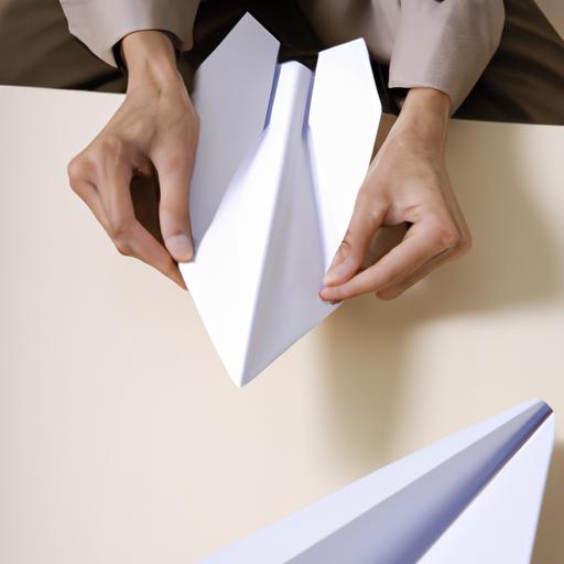 A person folds a sheet of paper to make the perfect paper airplane.